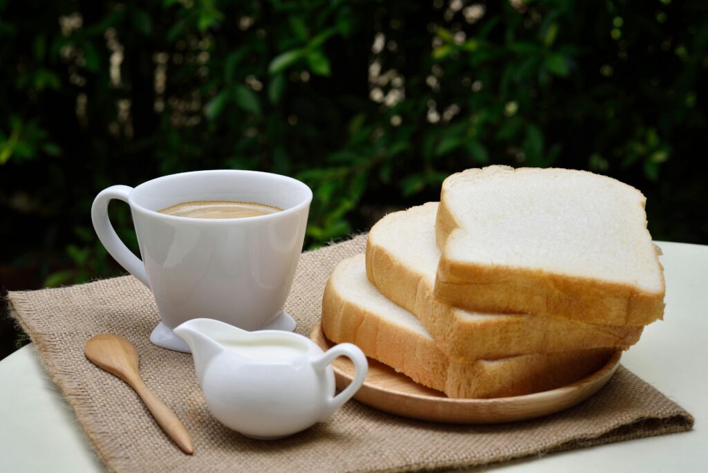 A cozy breakfast setup with fresh bread and a steaming cup of coffee outdoors.