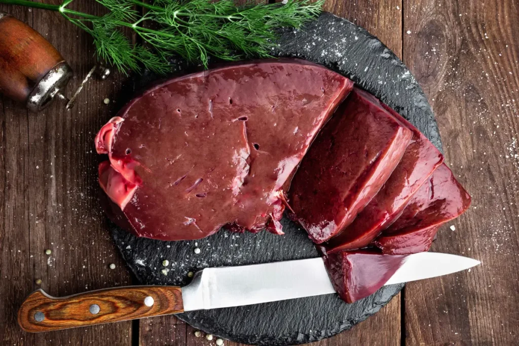 Potongan hati sapi segar berwarna merah tua mengkilap dengan permukaan yang kesat dan padat di atas talenan dapur higienis.